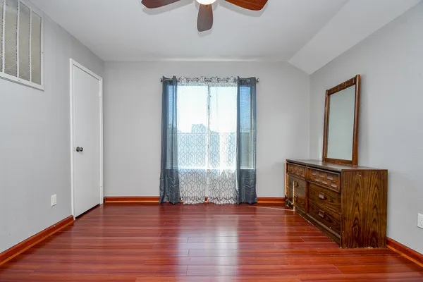 an empty room with wooden floor cabinet and windows