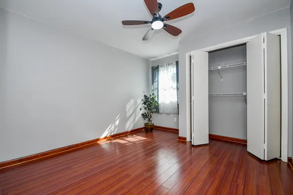 a view of a big room with wooden floor and a ceiling fan