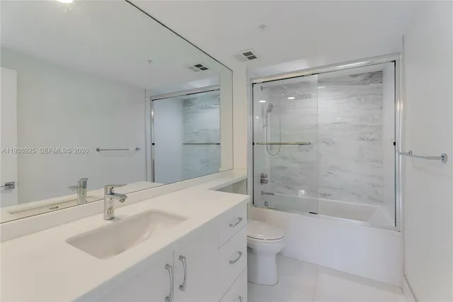 a bathroom with a shower sink vanity mirror and toilet
