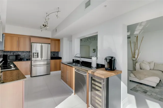 a kitchen with stainless steel appliances granite countertop a refrigerator a stove a sink a dining table and chairs with wooden floor