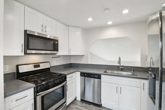 a kitchen with granite countertop a sink stove and microwave
