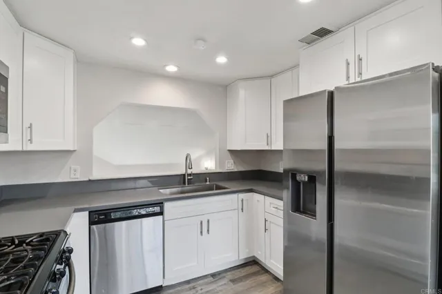 a kitchen with granite countertop a sink stainless steel appliances and cabinets