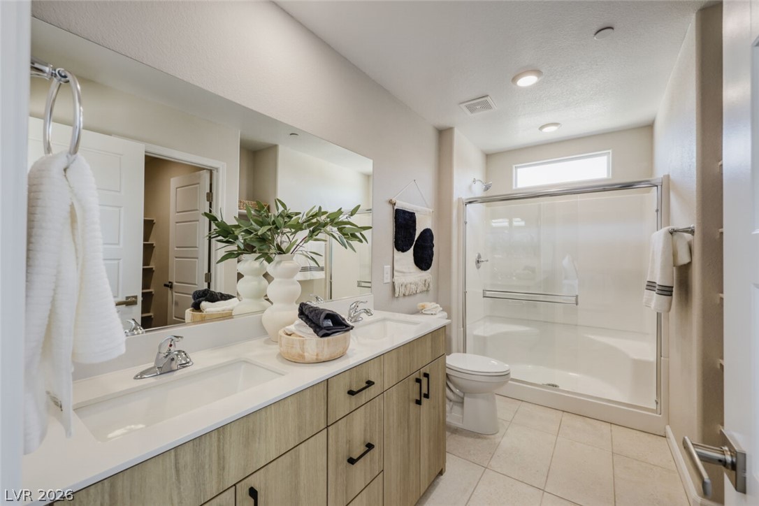911 Cadence View Way Henderson, NV 89011 - Photo 16 of 28 This primary bathroom features a dual vanity, a large walk-in shower, and ample storage.