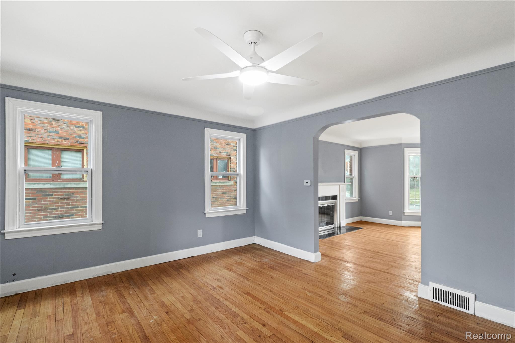 4834 Devonshire Road Detroit, MI 48224 - Photo 8 of 22 Empty room featuring hardwood / wood-style flooring, arched walkways, a fireplace with flush hearth, and a ceiling fan