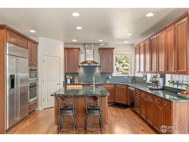 a kitchen with stainless steel appliances granite countertop sink stove refrigerator and cabinets