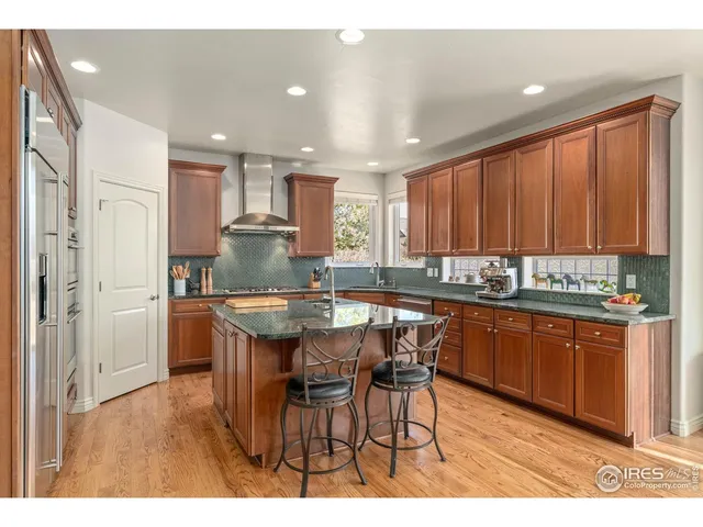 a kitchen with stainless steel appliances granite countertop a table chairs sink refrigerator and cabinets
