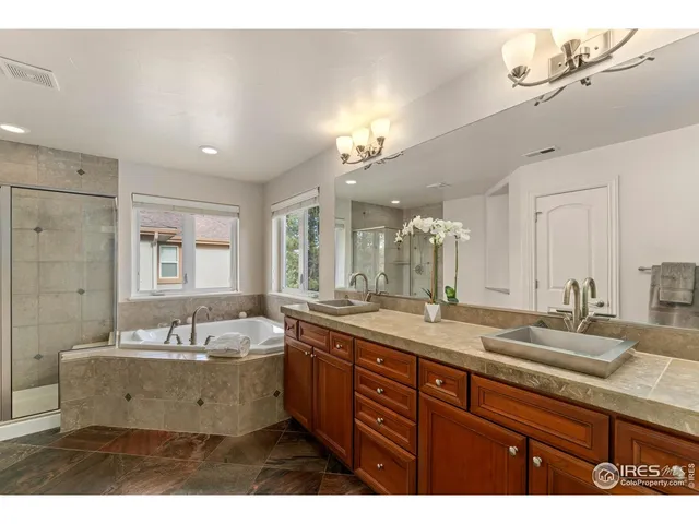 a bathroom with a sink double vanity granite tub shower and a mirror