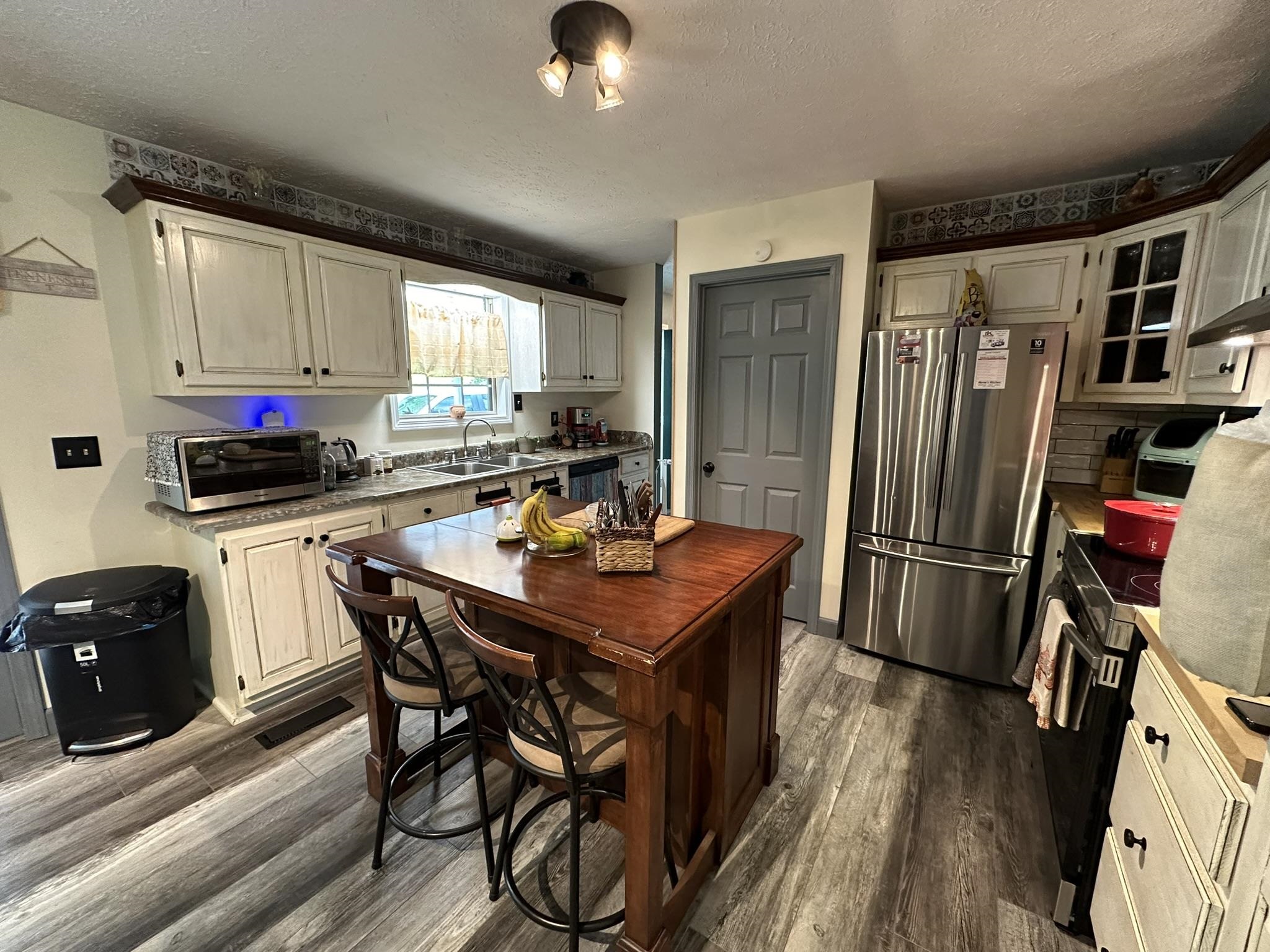 576 Carroll Hollow Road Waynesboro, TN 38485 - Photo 11 of 40 a kitchen with stainless steel appliances a stove a refrigerator a sink a dining table and chairs with wooden floor