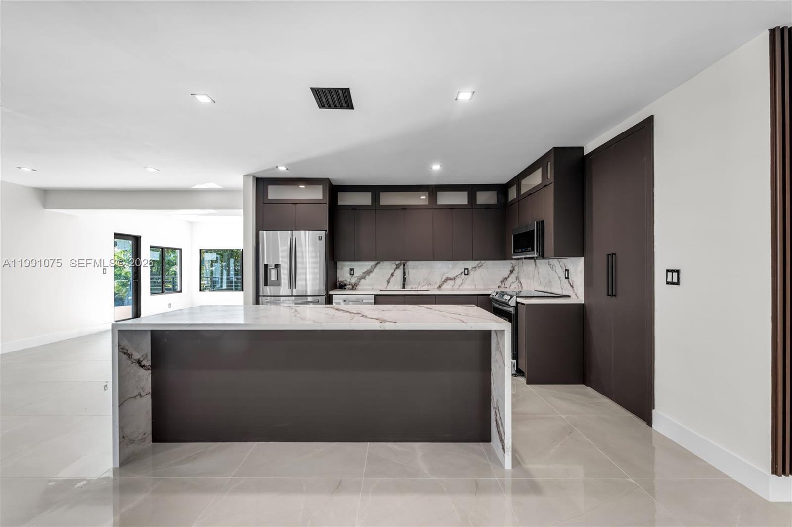 7920 Southwest 132nd Street Pinecrest, FL 33156 - Photo 6 of 45 a large kitchen with kitchen island a sink stainless steel appliances and cabinets