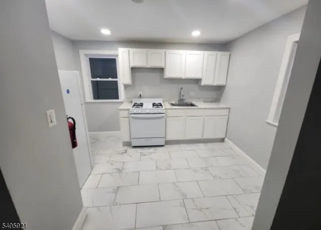 a kitchen with white cabinets a sink stove and refrigerator