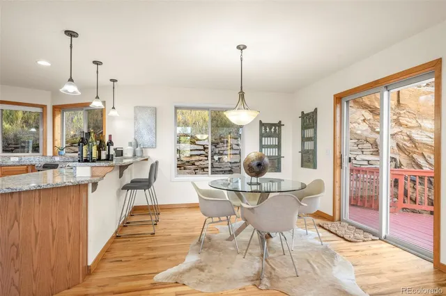 a dining room with stainless steel appliances granite countertop a table chairs and a view of living room