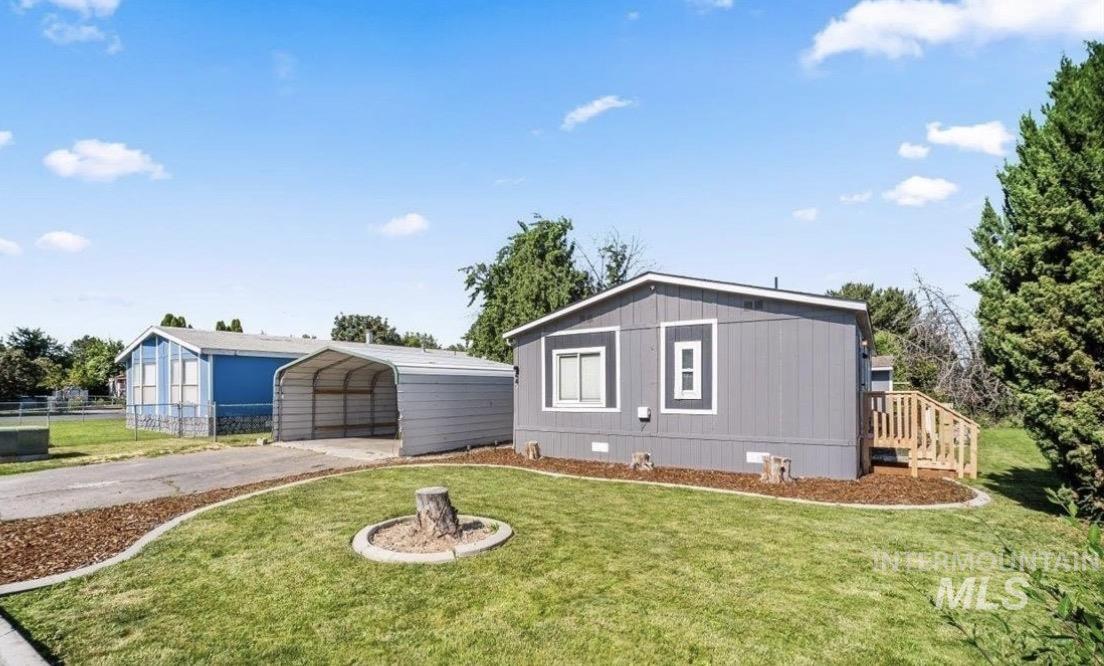 Exterior featuring gray siding with white trim, a wooden deck, and a manicured lawn