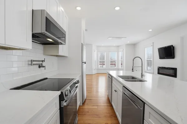 a kitchen with stainless steel appliances granite countertop a sink a stove and a refrigerator