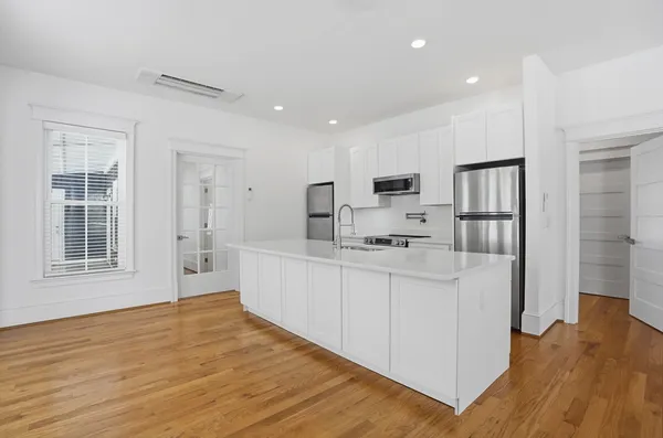 a large white kitchen with white cabinets and wooden floor