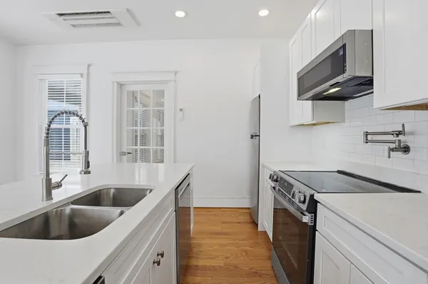 a kitchen with stainless steel appliances granite countertop a sink and a white cabinets