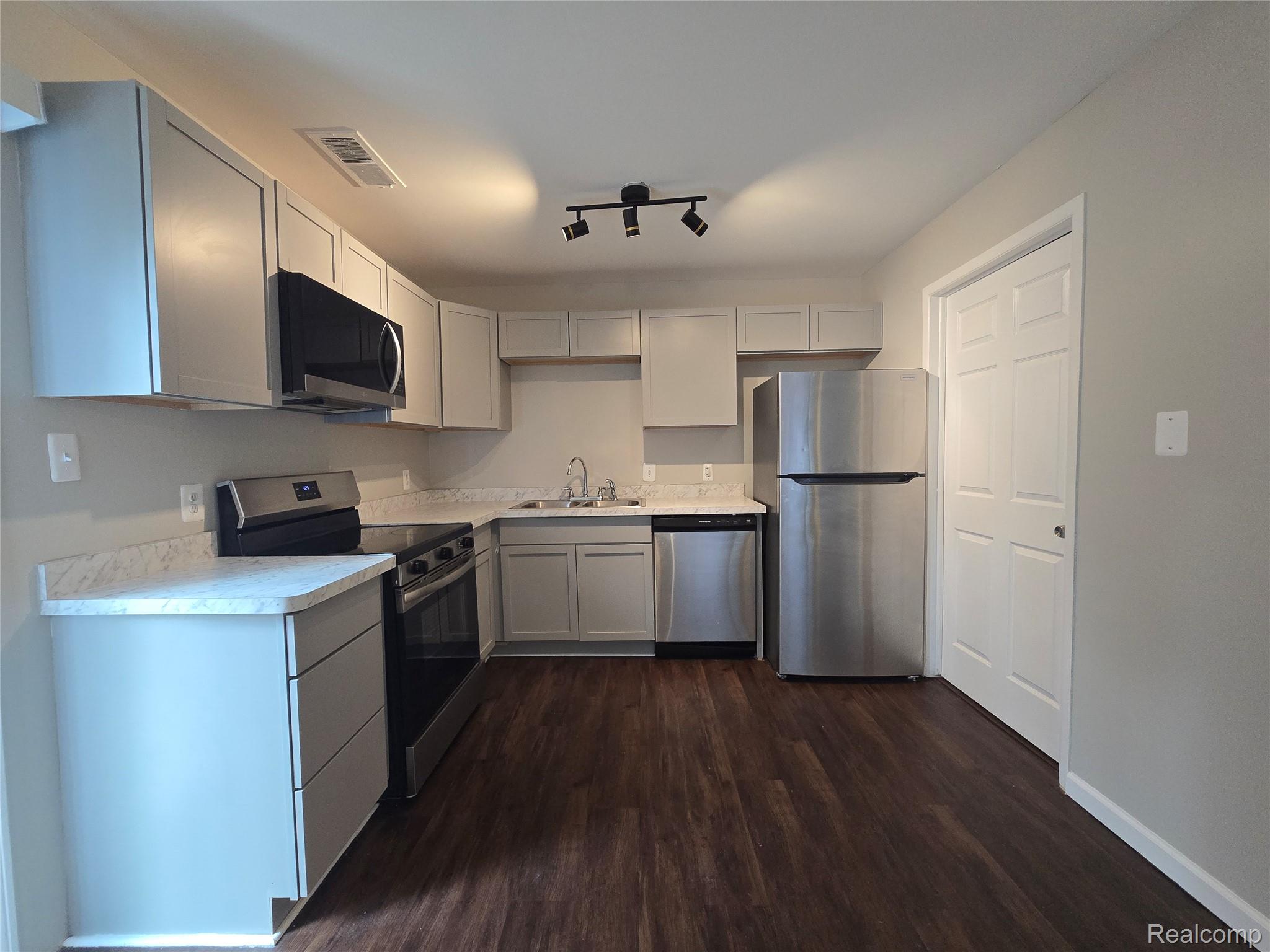 23568 Lahser Road Southfield, MI 48033 - Photo 6 of 18 Kitchen featuring wood-finish flooring, gray cabinetry, light-toned countertops, and stainless steel appliances