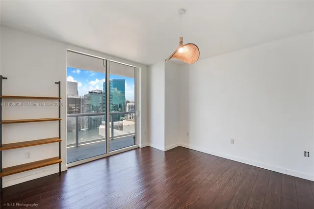 a view of an empty room with wooden floor and window