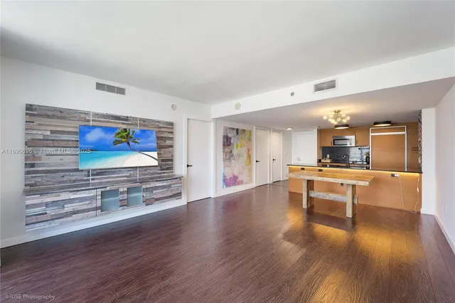 a living room with stainless steel appliances kitchen island hard wood floors and furniture
