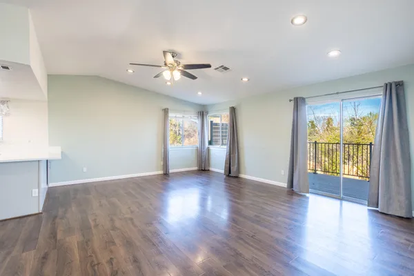 a view of an empty room with a window and wooden floor