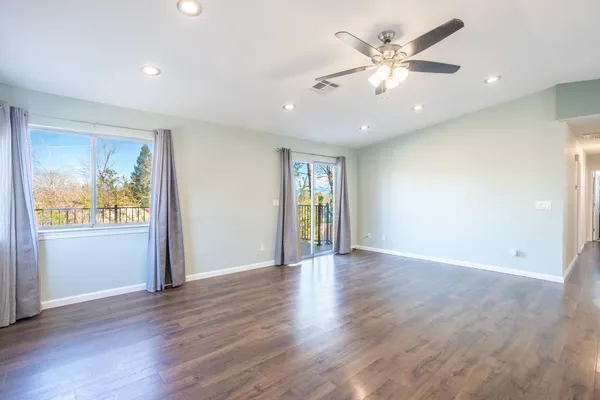 a view of an empty room with window and wooden floor