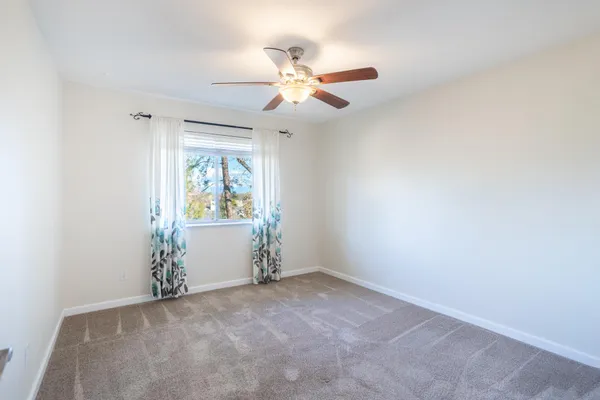 an empty room with window and ceiling fan