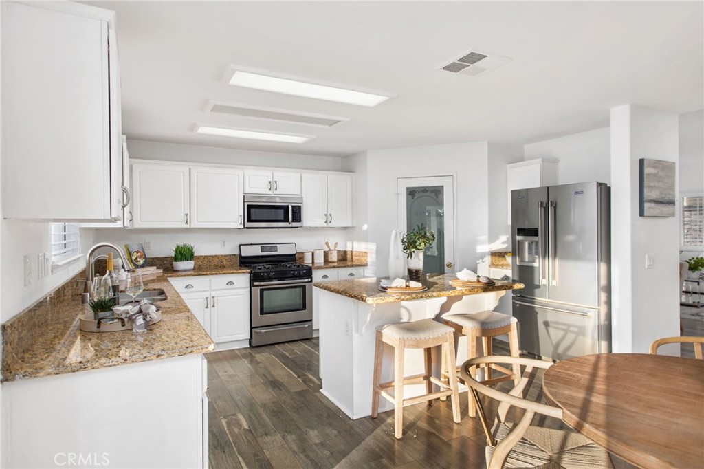 33686 Abbey Road Temecula, CA 92592 - Photo 10 of 37 a kitchen with stainless steel appliances granite countertop a stove top oven a sink dishwasher a dining table and chairs with wooden floor