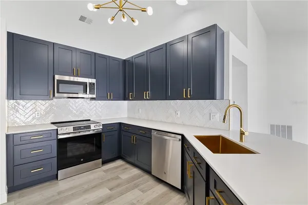 a kitchen with granite countertop stainless steel appliances cabinets a sink and a stove