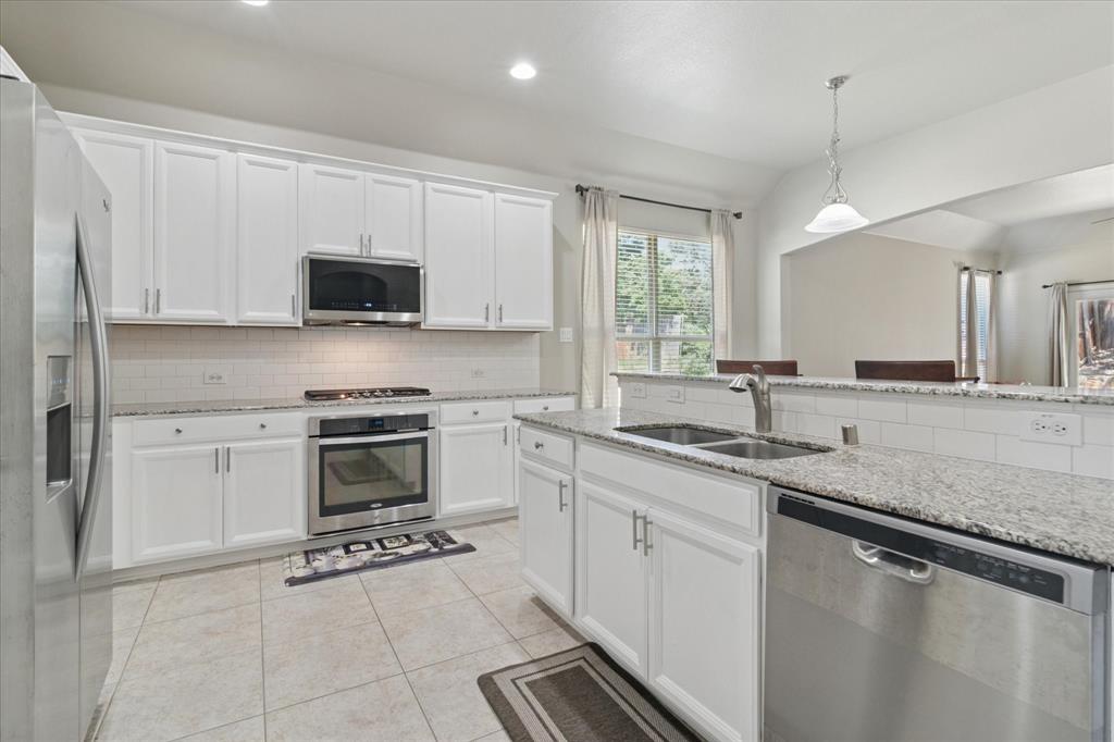 7401 Bishop Pine Road Denton, TX 76208 - Photo 7 of 25 a kitchen with granite countertop a sink a stove top oven and cabinetry