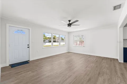 a view of an empty room with a window and wooden floor