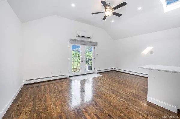 an empty room with wooden floor fan and windows