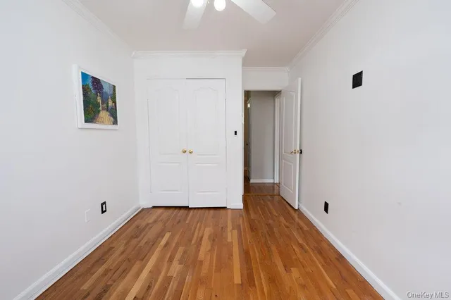 a view of a hallway with wooden floor and a ceiling fan