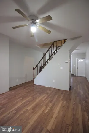 a view of an empty room with wooden floor and stairs
