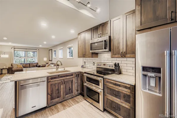 a kitchen with stainless steel appliances a stove sink refrigerator and cabinets