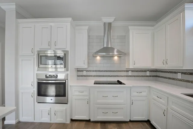 a kitchen with white cabinets and stainless steel appliances