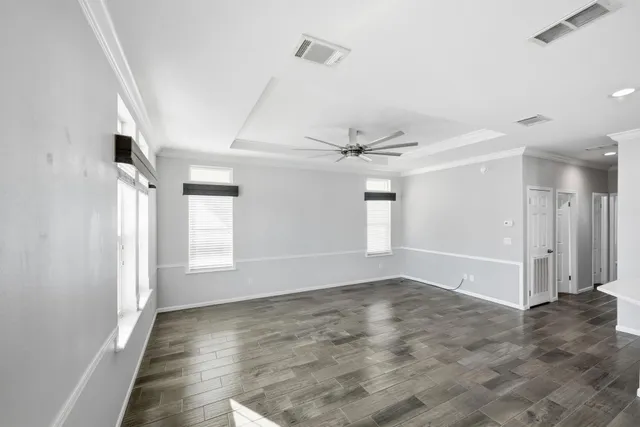 a view of empty room with wooden floor and fan