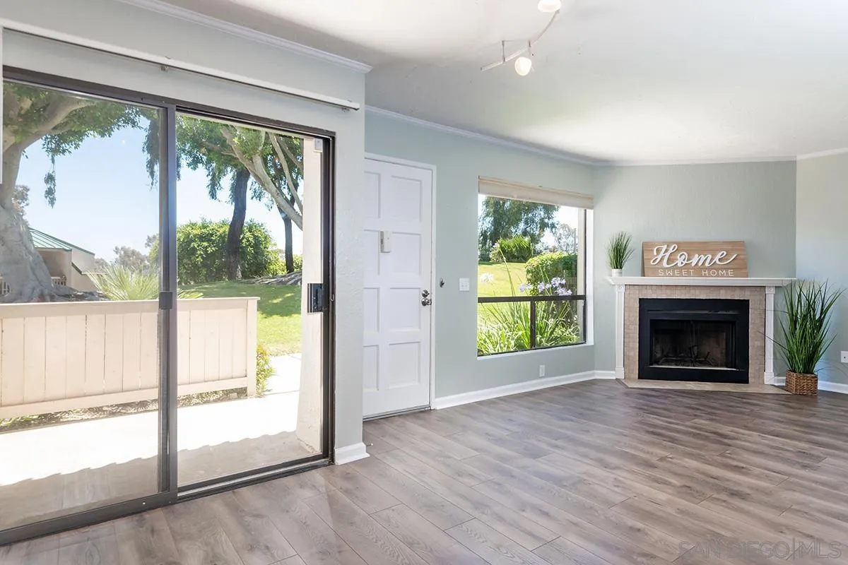 an empty room with wooden floor a fireplace and windows
