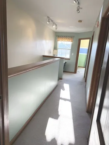 a view of a hallway to an empty room with wooden floor and a window