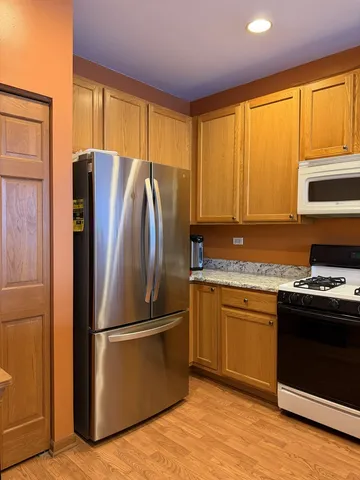 a kitchen with granite countertop stainless steel appliances a refrigerator cabinets and a window