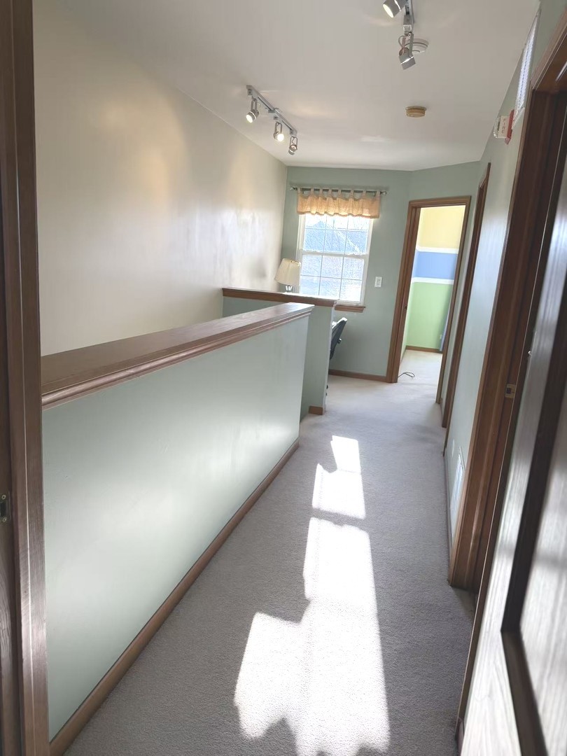 864 Genesee Drive Naperville, IL 60563 - Photo 10 of 31 a view of a hallway to an empty room with wooden floor and a window