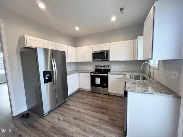 a kitchen with kitchen island granite countertop a refrigerator stove and sink