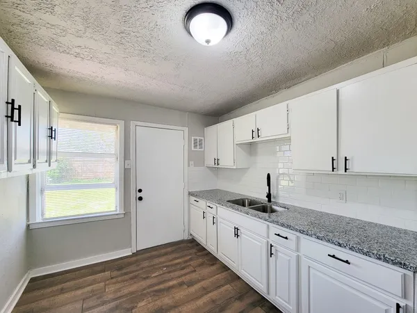 a kitchen with granite countertop white cabinets and a window