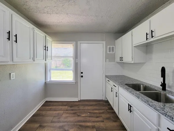 a kitchen with granite countertop white cabinets and a sink