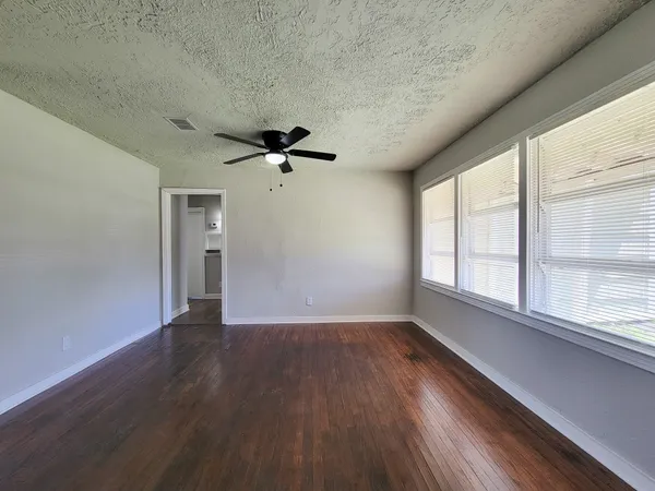 a view of an empty room with a window and wooden floor