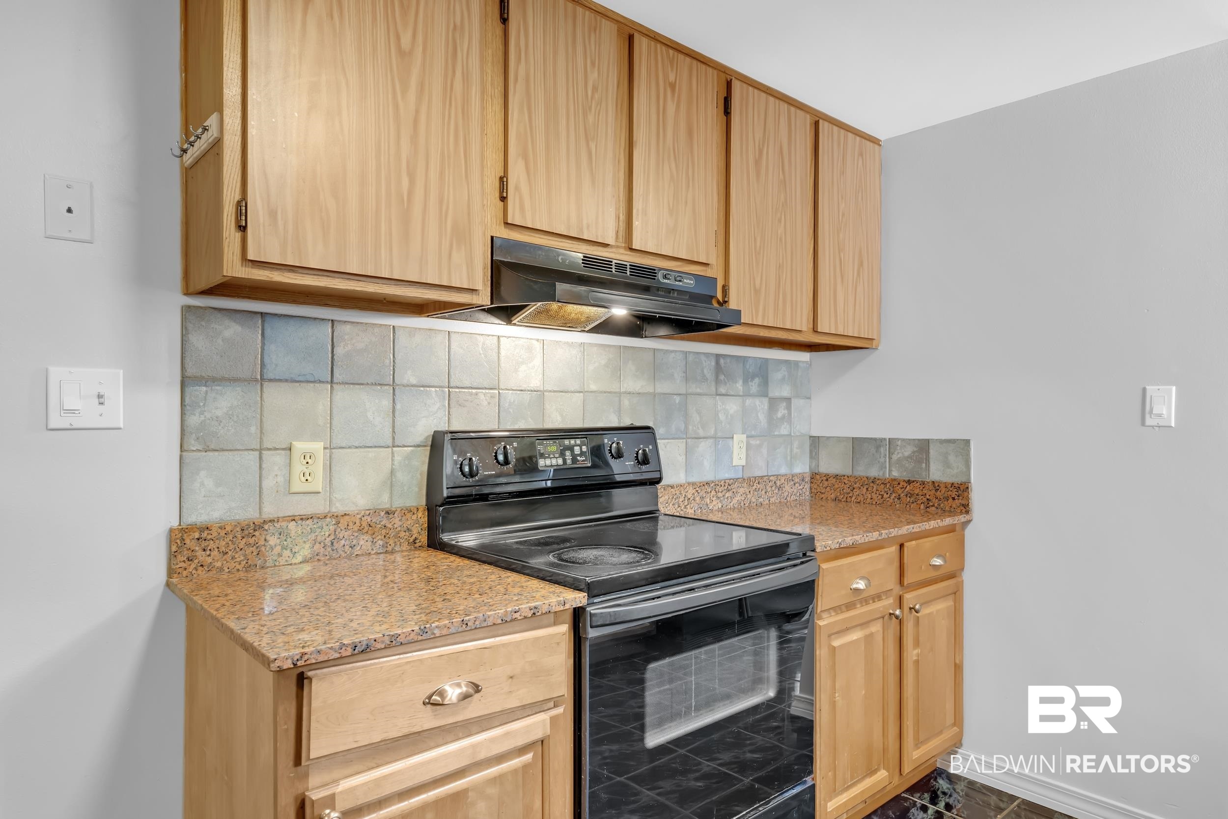 421 Cedar Court Foley, AL 36535 - Photo 20 of 39 Kitchen featuring wood cabinetry, granite-finish countertops, tiled backsplash, and a black electric range with an overhead vent hood