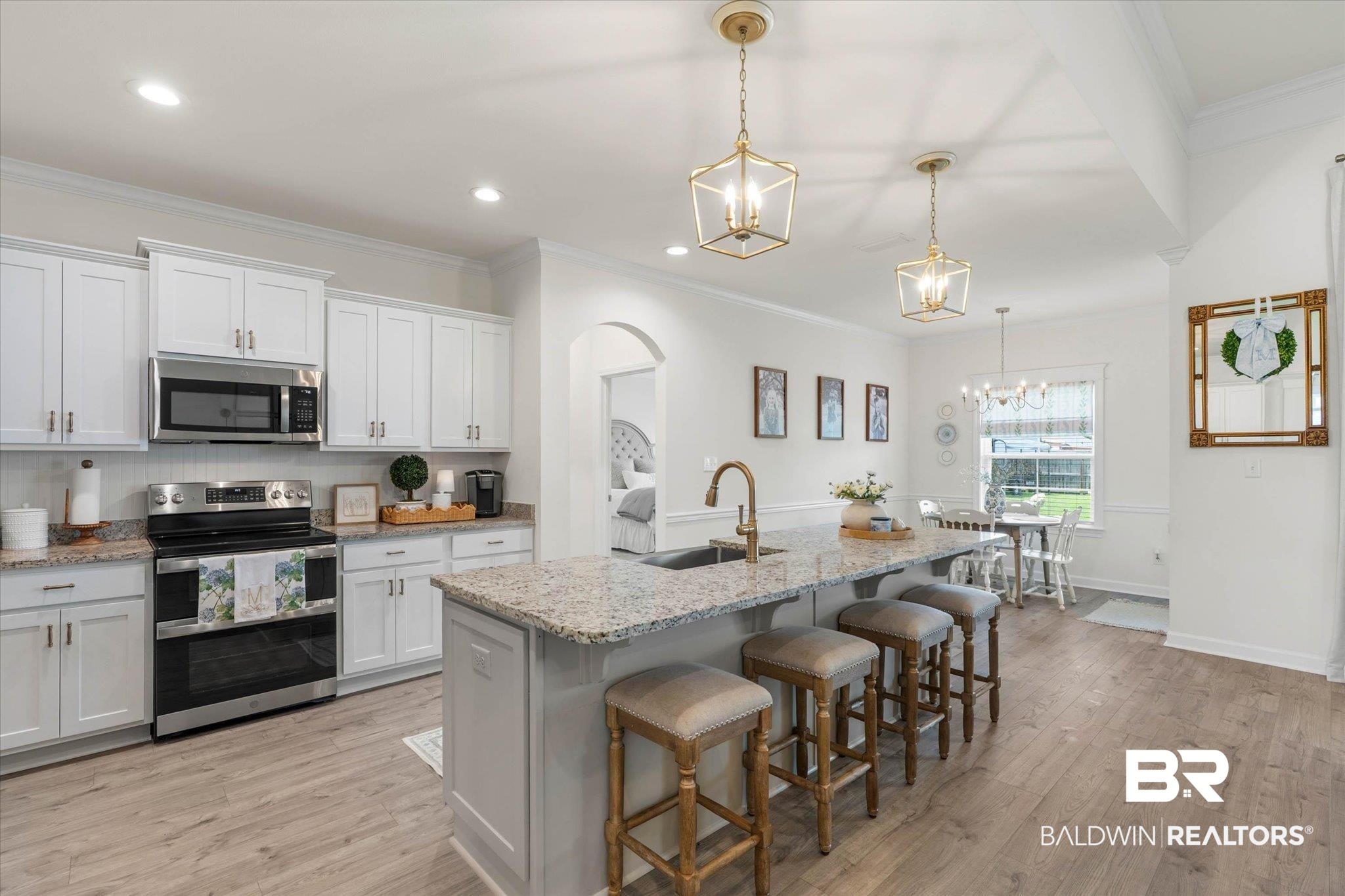 9074 Moses Way Theodore, AL 36582 - Photo 16 of 52 Open-concept kitchen featuring an expansive island with a granite countertop, a stainless steel appliance suite, white cabinetry, and wood-finish flooring