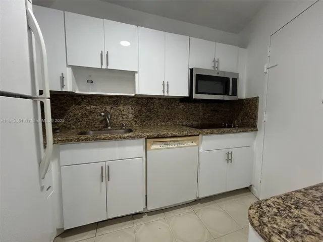 a kitchen with stainless steel appliances granite countertop white cabinets sink and a granite counter top