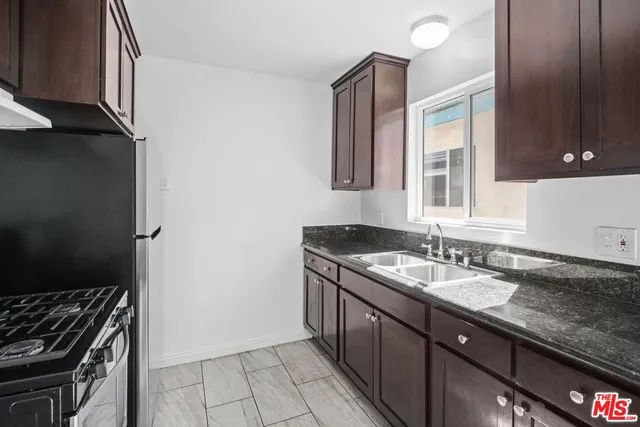 a kitchen with granite countertop a sink stove and cabinets