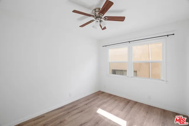 a view of an empty room with a window and wooden floor