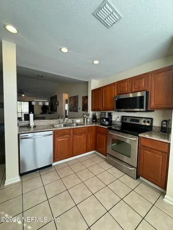 a kitchen with granite countertop a refrigerator and a stove top oven