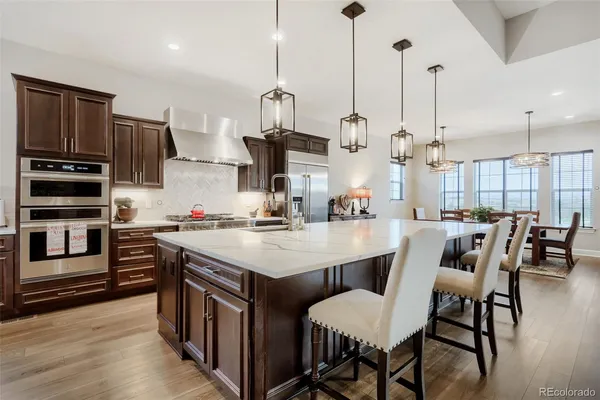 a kitchen with stainless steel appliances kitchen island granite countertop a table chairs in it and wooden floors